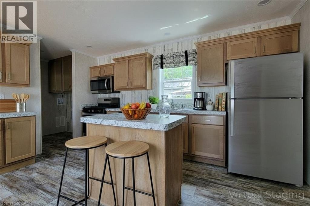 Kitchen featuring stainless steel appliances, a kitchen breakfast bar, a center island, light countertops, and crown molding - 77 Park Lane, Flamborough, ON - Indoor Photo Showing Kitchen