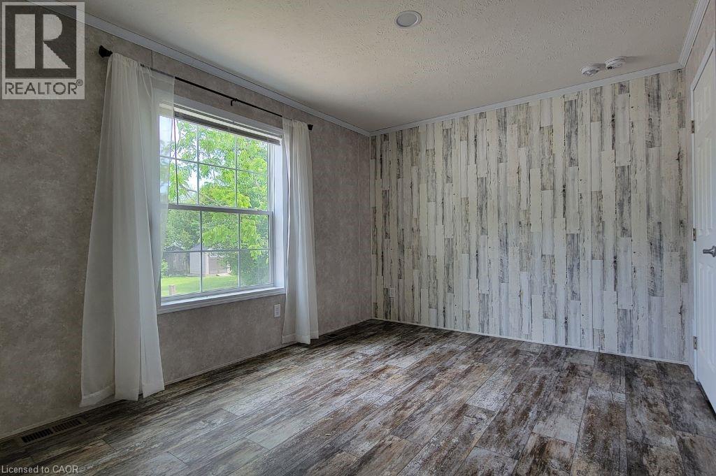 Empty room with wood finished floors, crown molding, and a textured ceiling - 77 Park Lane, Flamborough, ON - Indoor Photo Showing Other Room