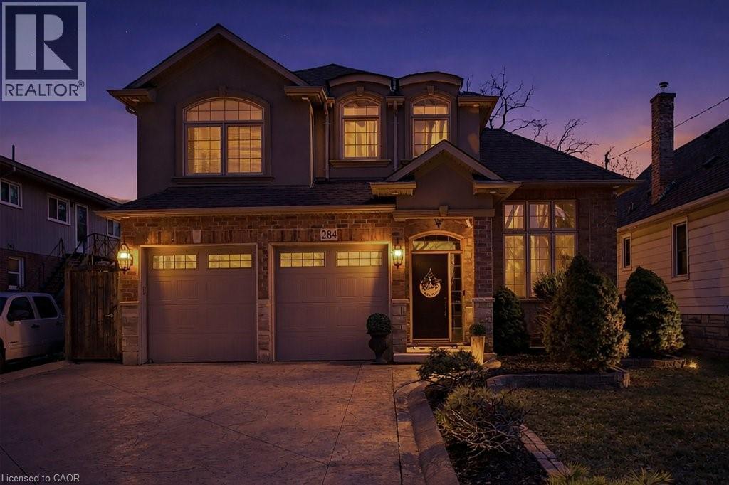 View of front of home with an attached garage, concrete driveway, stucco siding, a shingled roof, and stone siding - 284 Normanhurst Avenue, Hamilton, ON - Outdoor