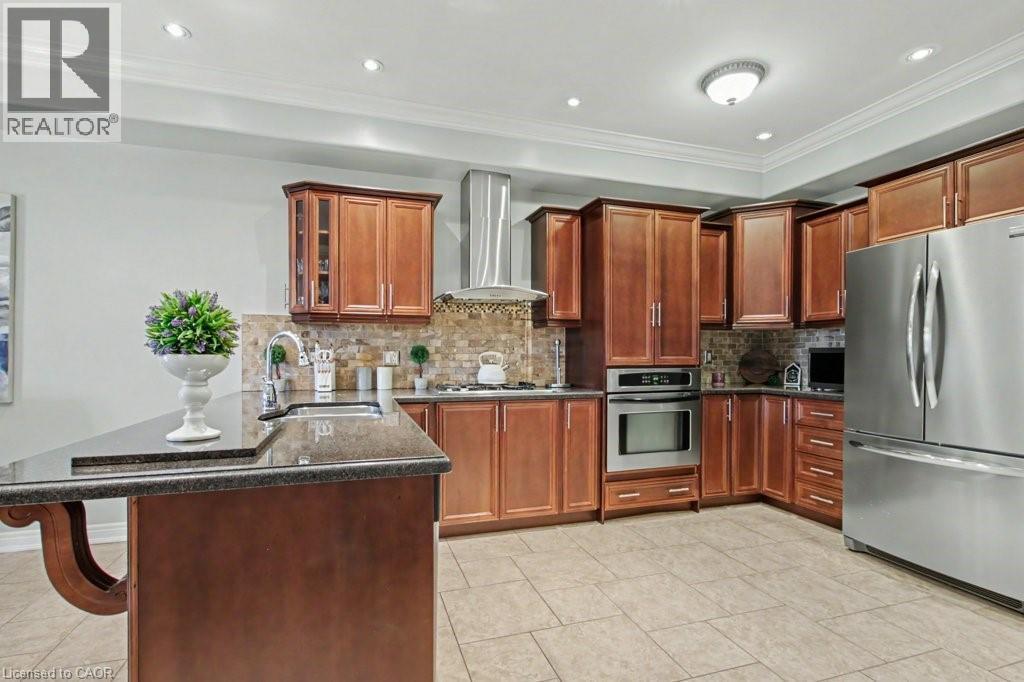 Kitchen with stainless steel appliances, a peninsula, dark stone counters, a breakfast bar area, and crown molding - 284 Normanhurst Avenue, Hamilton, ON - Indoor Photo Showing Kitchen