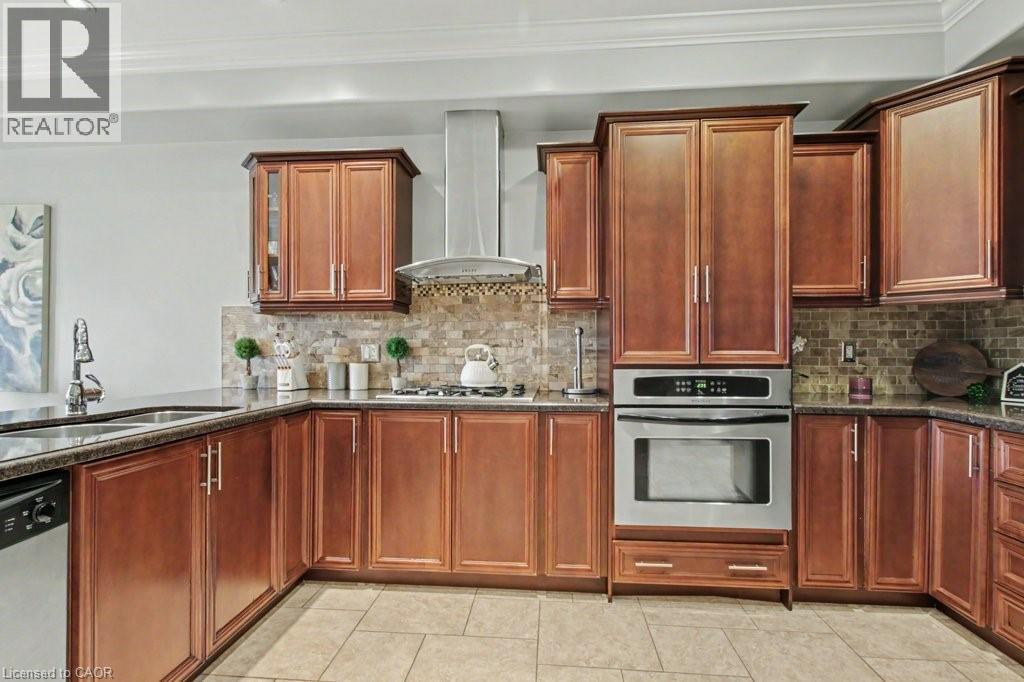 Kitchen with stainless steel appliances, dark stone countertops, glass fronted cabinets, crown molding, and light tile patterned floors - 284 Normanhurst Avenue, Hamilton, ON - Indoor Photo Showing Kitchen With Double Sink
