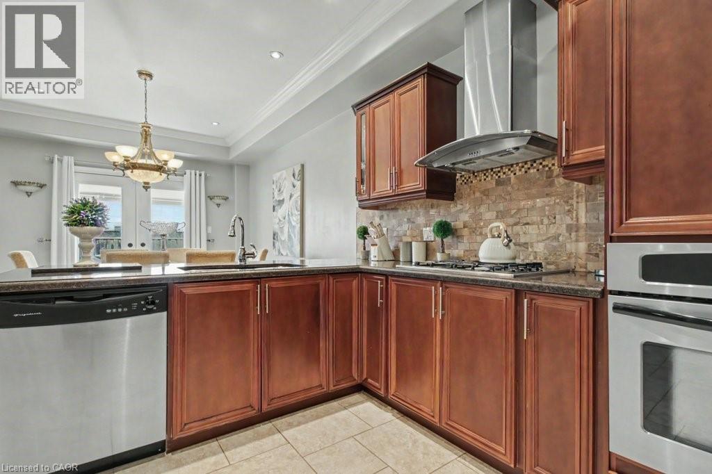 Kitchen with hanging lights, stainless steel appliances, bold wood finish cabinetry, backsplash, and a tray ceiling - 284 Normanhurst Avenue, Hamilton, ON - Indoor Photo Showing Kitchen