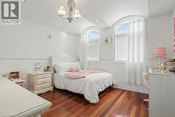 Bedroom featuring dark wood finished floors, hanging lights, and lofted ceiling -