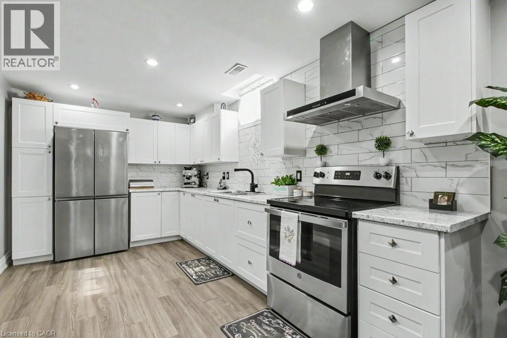 Kitchen featuring stainless steel appliances, range hood, white cabinetry, light wood-style floors, and light stone countertops - 284 Normanhurst Avenue, Hamilton, ON - Indoor Photo Showing Kitchen With Upgraded Kitchen