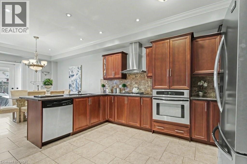 Kitchen featuring stainless steel appliances, crown molding, a peninsula, suspended lighting, and tasteful backsplash - 284 Normanhurst Avenue, Hamilton, ON - Indoor Photo Showing Kitchen With Double Sink