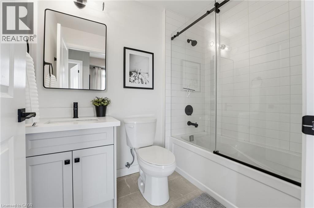 Bathroom with vanity, bath / shower combo with glass door, and light tile patterned flooring - 120 Springvalley Crescent Unit# 203, Hamilton, ON - Indoor Photo Showing Bathroom