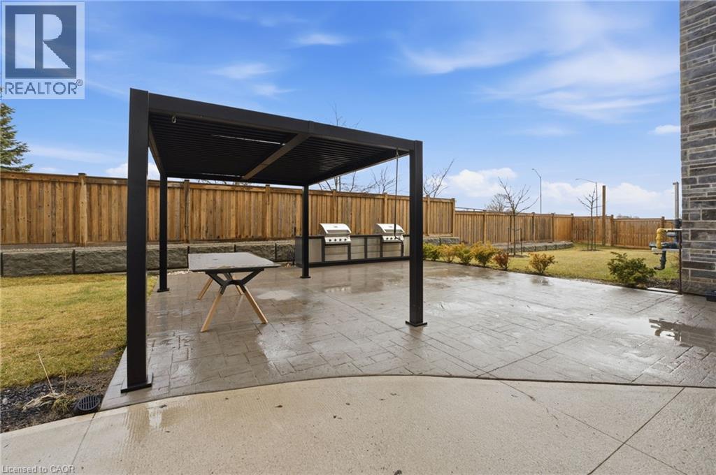 Fenced common backyard featuring a patio area and area for grilling - 120 Springvalley Crescent Unit# 203, Hamilton, ON - Outdoor