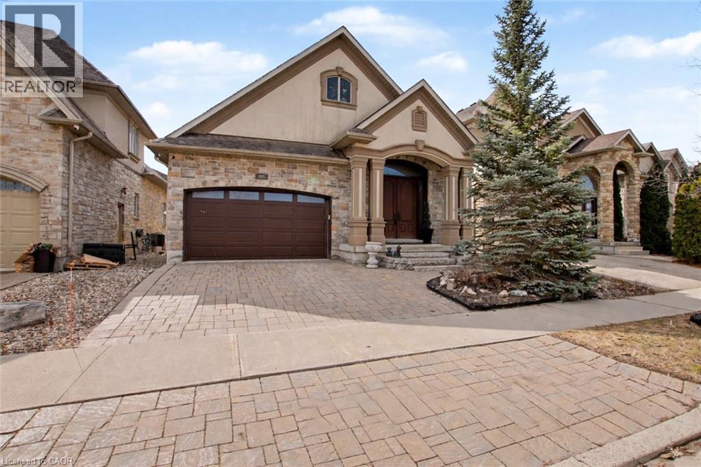 French country style house featuring decorative driveway, stucco siding, an attached garage, and stone siding - 205 Paige Place, Kitchener, ON - Outdoor With Facade