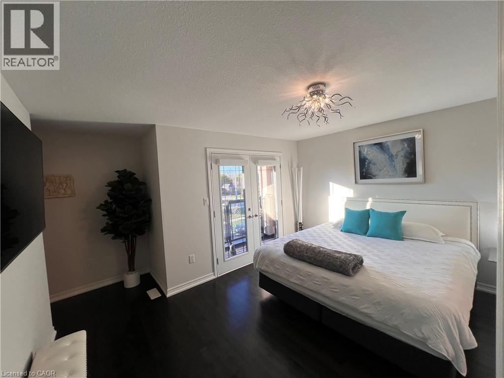 Bedroom with dark wood-style floors, access to exterior, a textured ceiling, and french doors - 1165 West 5Th Street, Hamilton, ON - Indoor Photo Showing Bedroom