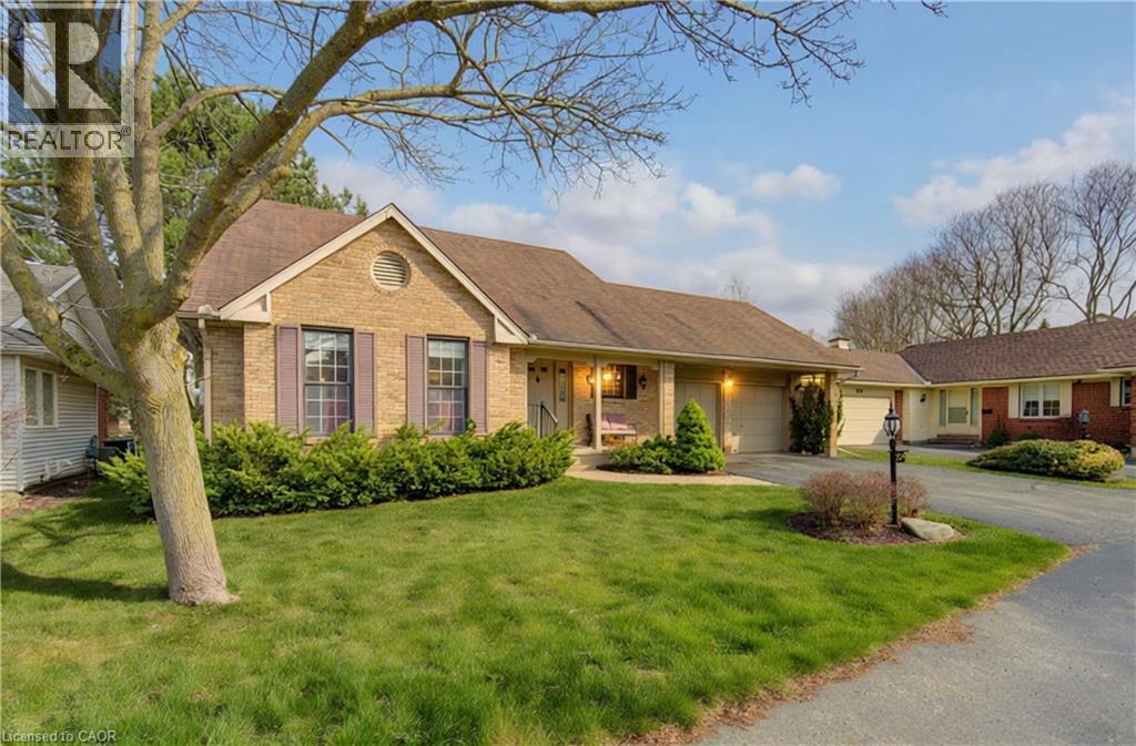 Ranch-style home with brick siding, a porch, a front lawn, an attached garage, and driveway - 306 Roxton Drive, Waterloo, ON - Outdoor With Facade