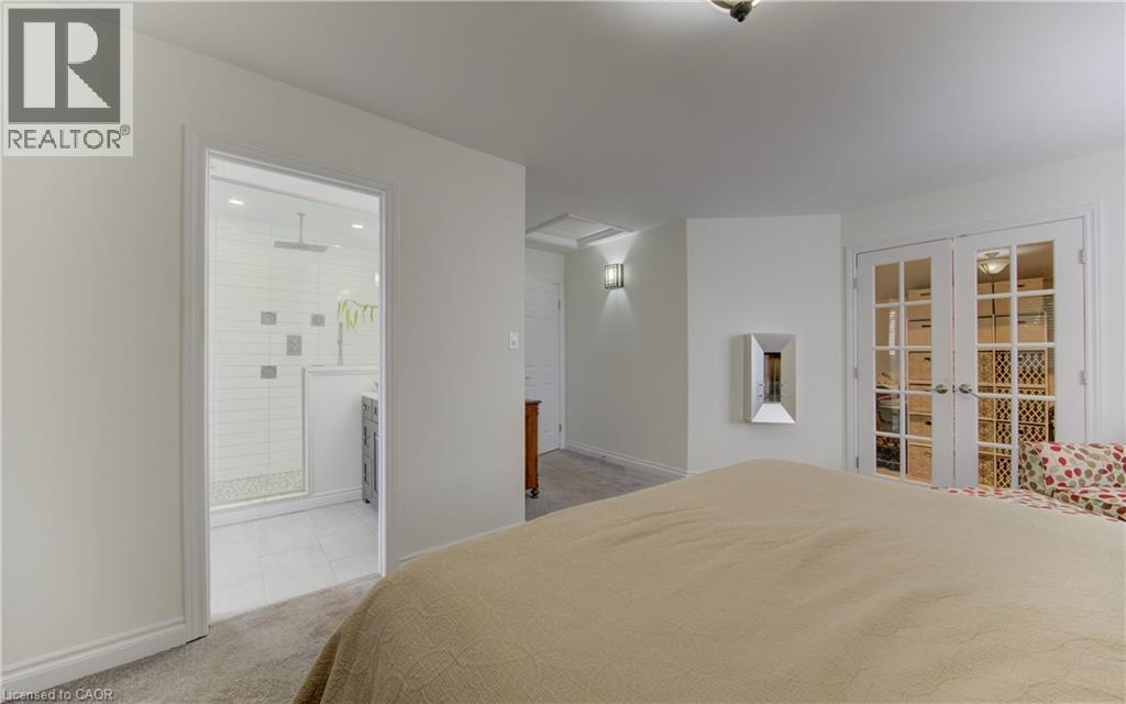 Bedroom with french doors, light colored carpet, and connected bathroom - 306 Roxton Drive, Waterloo, ON - Indoor Photo Showing Bedroom