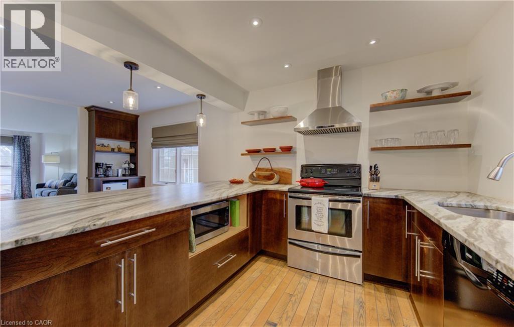 Kitchen with stainless steel appliances, ventilation hood, hanging light fixtures, light wood finished floors, and open shelves - 306 Roxton Drive, Waterloo, ON - Indoor Photo Showing Kitchen