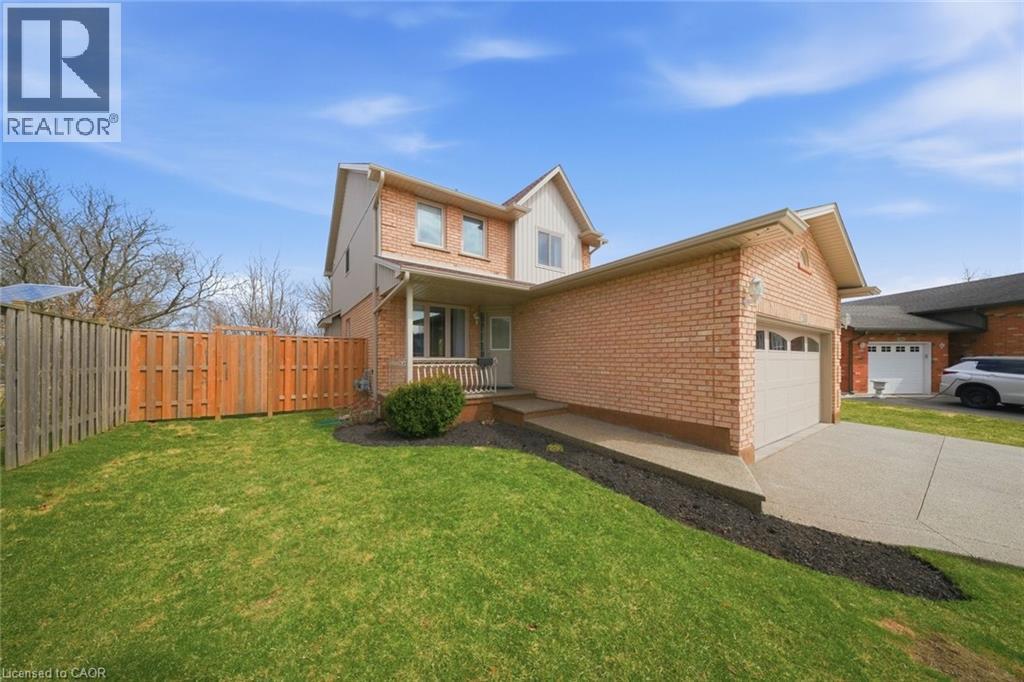 View of front facade featuring a garage, concrete driveway, brick siding, and board and batten siding - 200 Morrison Drive, Caledonia, ON - Outdoor