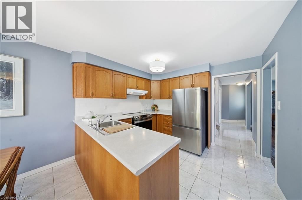 Kitchen featuring stainless steel appliances, wood finish cabinetry, light countertops, and light tile patterned floors - 200 Morrison Drive, Caledonia, ON - Indoor Photo Showing Kitchen