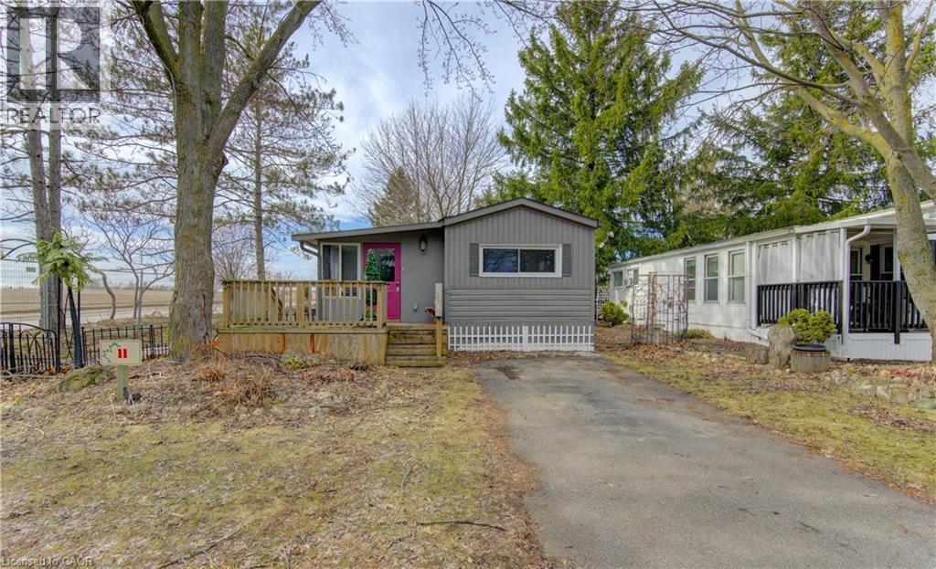 Manufactured / mobile home featuring a wooden deck and asphalt driveway - 580 Beaver Creek Road Unit# 11, Waterloo, ON - Outdoor