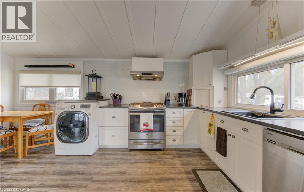Kitchen with plenty of natural light, stainless steel appliances, washer / dryer, and white cabinetry - 580 Beaver Creek Road Unit# 11, Waterloo, ON - Indoor Photo Showing Laundry Room