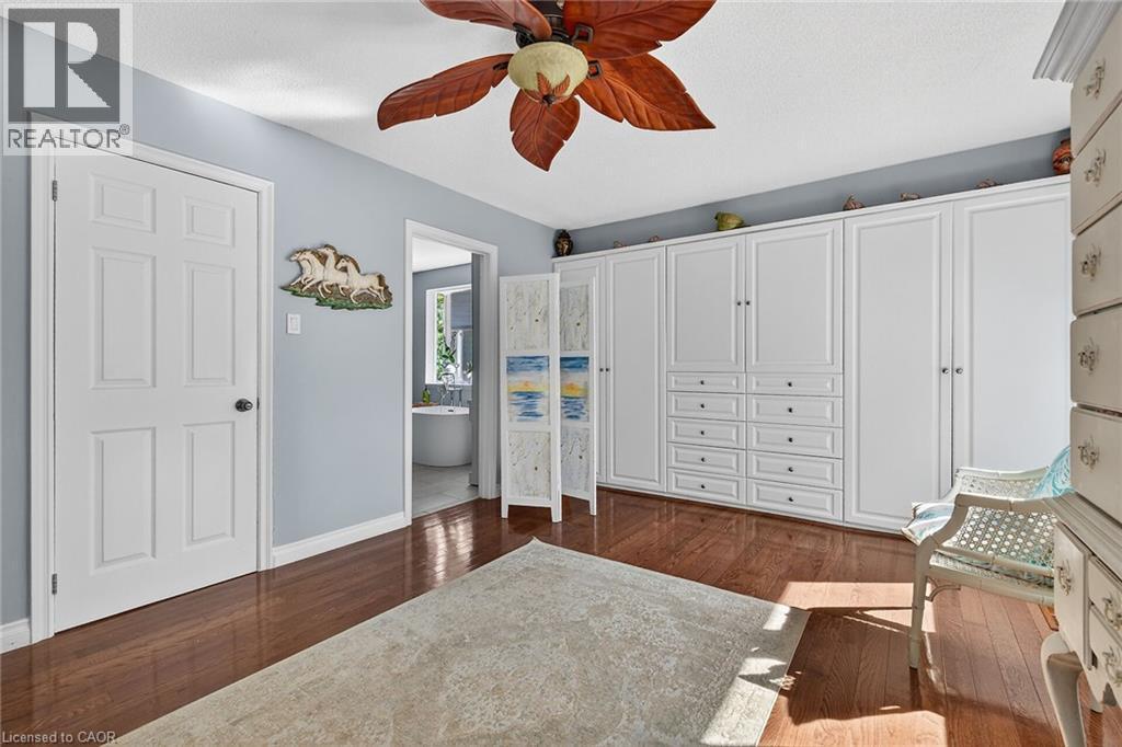 Bedroom with dark wood finished floors, ceiling fan, and connected bathroom - 5590 Blind Line, Burlington, ON - Indoor