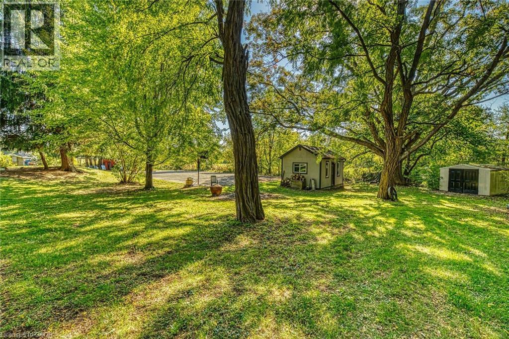 View of grassy yard featuring a storage shed and view of scattered trees - 5590 Blind Line, Burlington, ON - Outdoor