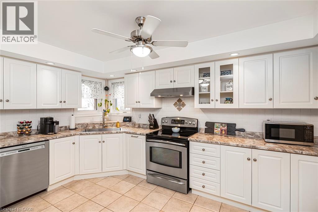 Kitchen with stainless steel appliances, white cabinets, glass insert cabinets, a ceiling fan, and recessed lighting - 40 Artistic Boulevard, Hamilton, ON - Indoor Photo Showing Kitchen