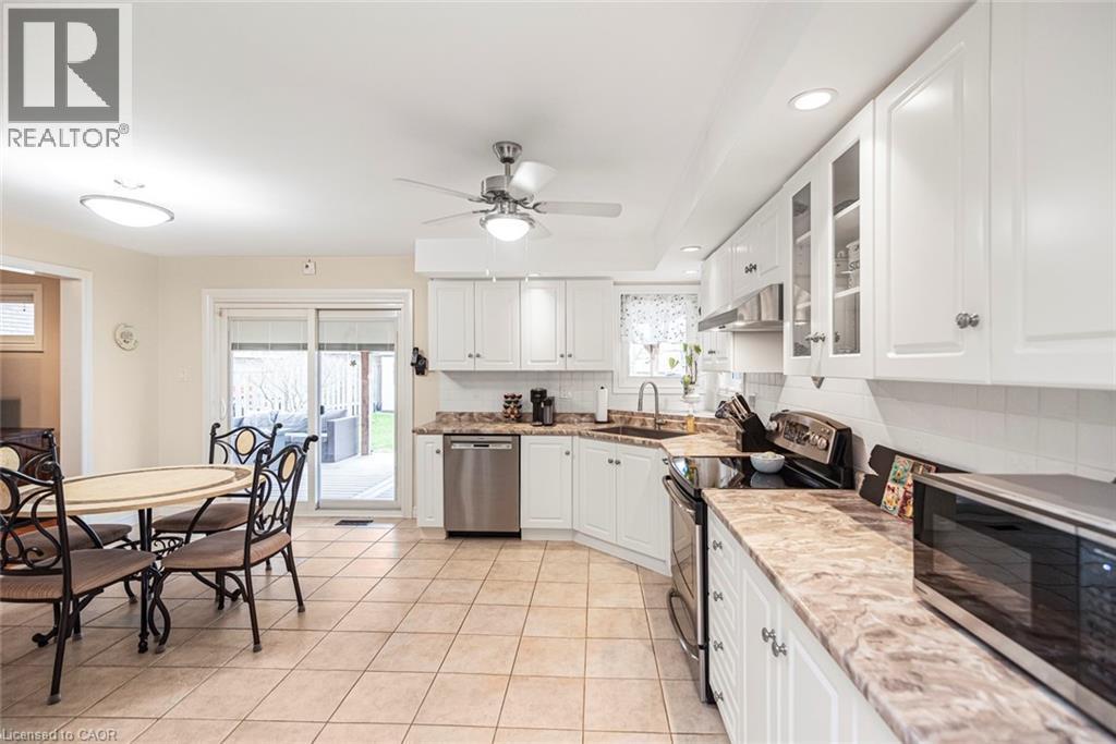 Kitchen with glass insert cabinets, stainless steel appliances, white cabinets, decorative backsplash, and ceiling fan - 40 Artistic Boulevard, Hamilton, ON - Indoor