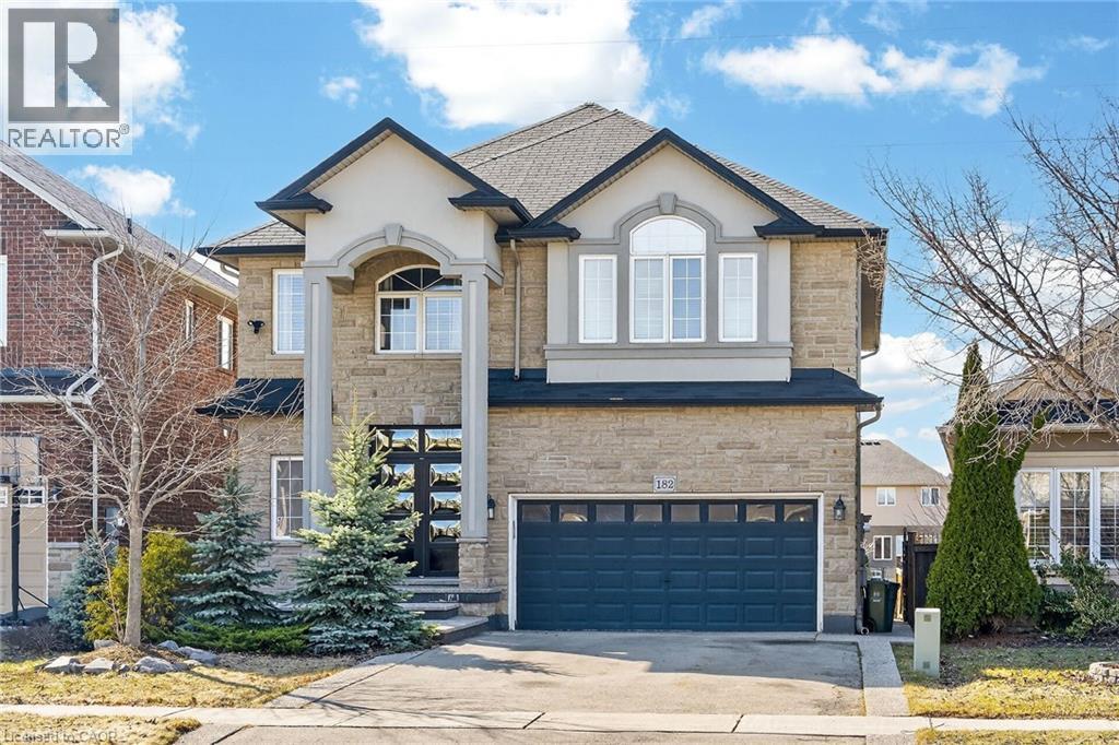 View of front of property with stone siding, an attached garage, driveway, and stucco and solid brick. - 182 Irwin Avenue, Hamilton, ON - Outdoor With Facade