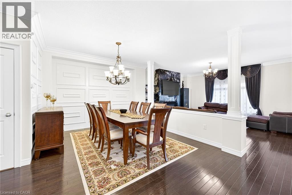 Dining room with a chandelier, ornamental molding, dark wood finished floors, and decorative columns - 182 Irwin Avenue, Hamilton, ON - Indoor Photo Showing Dining Room