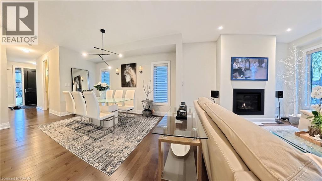 Kitchen with open floor plan, hardwood / wood-style floors, a glass covered fireplace, and healthy amount of natural light - 63 Ian Ormston Drive, Kitchener, ON - Indoor Photo Showing Other Room With Fireplace