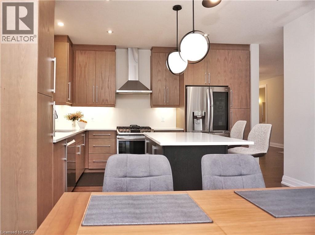 Kitchen with stainless steel appliances, a kitchen island, modern cabinets, a breakfast bar, and dark wood finished floors - 63 Ian Ormston Drive, Kitchener, ON - Indoor
