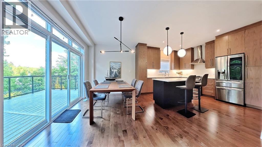 Kitchen featuring stainless steel refrigerator with ice dispenser, a center island, light wood-style floors, hanging light fixtures, and a kitchen breakfast bar - 63 Ian Ormston Drive, Kitchener, ON - Indoor Photo Showing Other Room