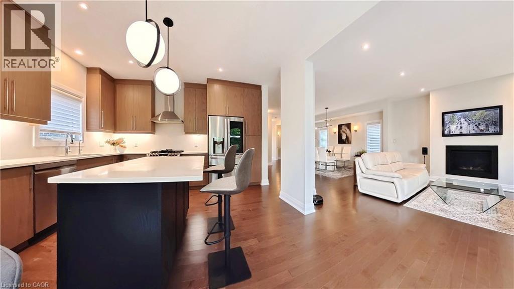 Kitchen with open floor plan, a center island, stainless steel appliances, hanging light fixtures, and a fireplace - 63 Ian Ormston Drive, Kitchener, ON - Indoor Photo Showing Kitchen With Upgraded Kitchen