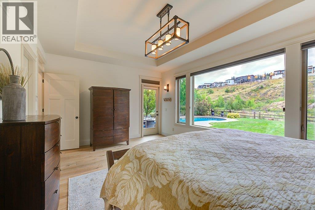 Main level Primary bedroom with easy access to the backyard & hot tub - 425 Audubon Court, Kelowna, BC - Indoor Photo Showing Bedroom