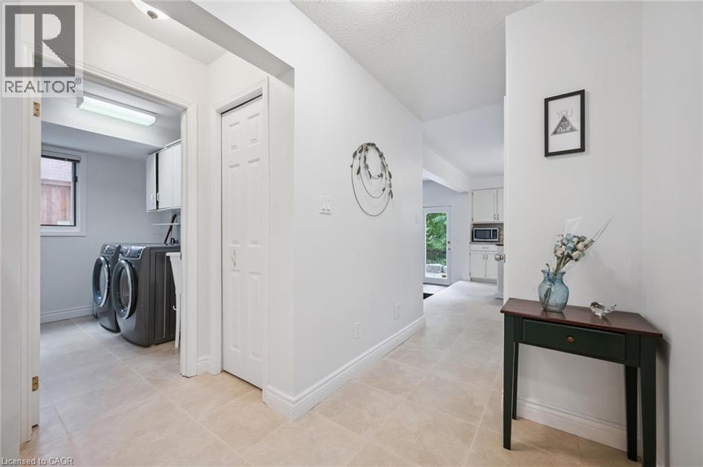 Hall featuring washing machine and dryer, light tile patterned floors, and a textured ceiling - 599 Beechwood Drive, Waterloo, ON - Indoor Photo Showing Laundry Room