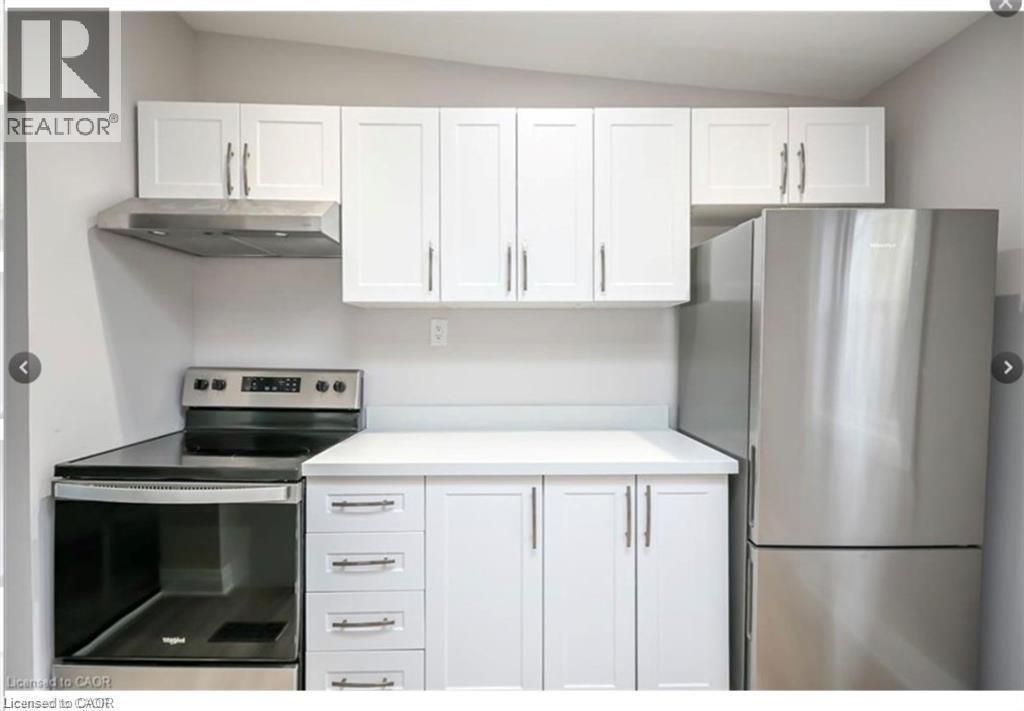 Kitchen with white cabinetry, stainless steel appliances, light countertops, and lofted ceiling - 1024 Cannon Street E, Hamilton, ON - Indoor Photo Showing Kitchen With Stainless Steel Kitchen