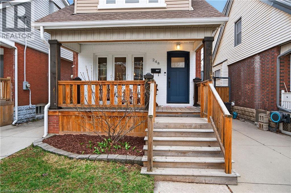 Entrance to property featuring a shingled roof, a porch, and brick siding - 248 London Street S, Hamilton, ON - Outdoor With Exterior