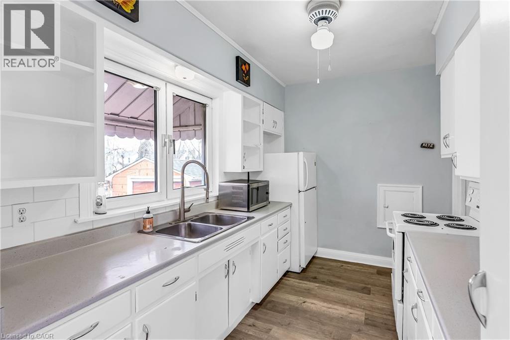 Kitchen featuring white electric range oven, white cabinetry, open shelves, light countertops, and stainless steel microwave - 41 Floral Crescent, Kitchener, ON - Indoor Photo Showing Kitchen With Double Sink