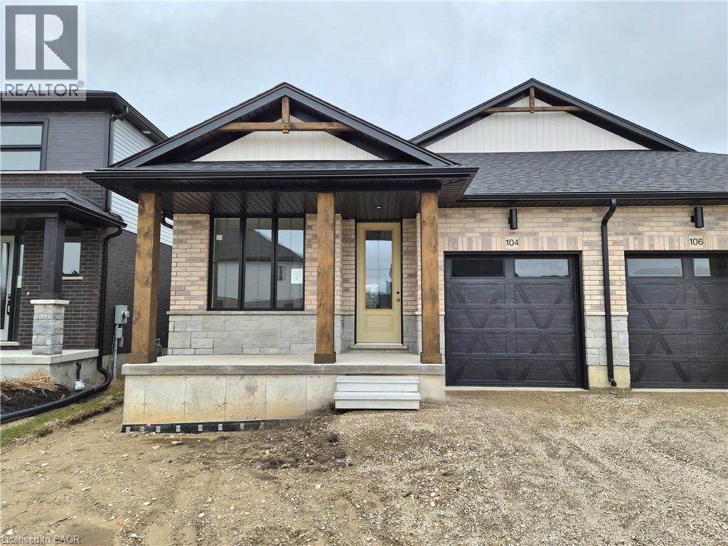 View of front of home with a garage, a porch, driveway, brick siding, and stone siding - 104 Thackeray Way, Harriston, ON - Outdoor With Facade