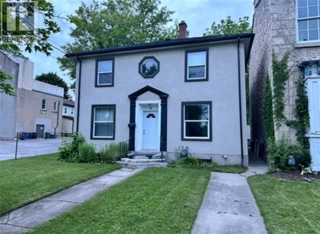 Colonial-style house featuring a front yard, stucco siding, and a chimney - 9 Waterloo Avenue, Guelph, ON - Outdoor With Facade