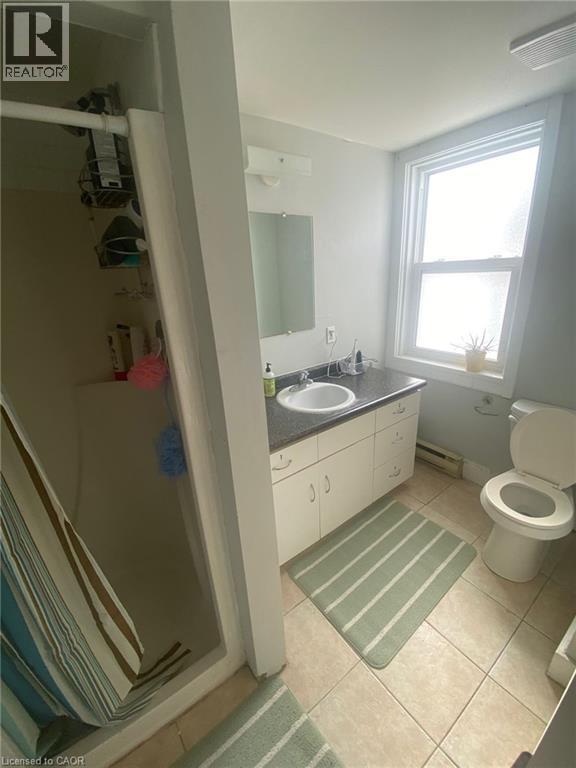 Full bath with vanity, light tile patterned floors, and a baseboard radiator - 9 Waterloo Avenue, Guelph, ON - Indoor Photo Showing Bathroom