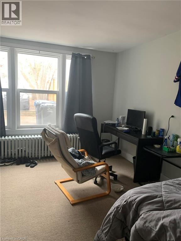 Carpeted bedroom with an office area and radiator heating unit - 9 Waterloo Avenue, Guelph, ON - Indoor