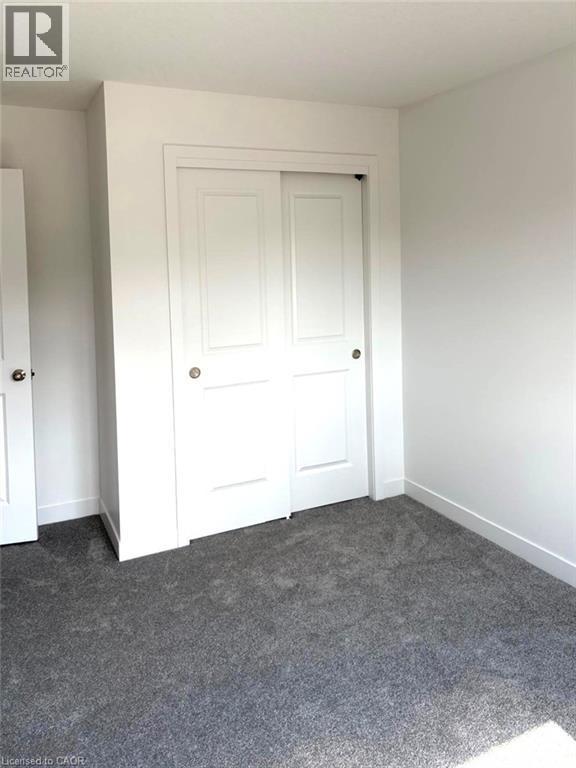 Unfurnished bedroom with dark carpet and a closet - 7 Pin Oak Common, Cambridge, ON - Indoor Photo Showing Other Room