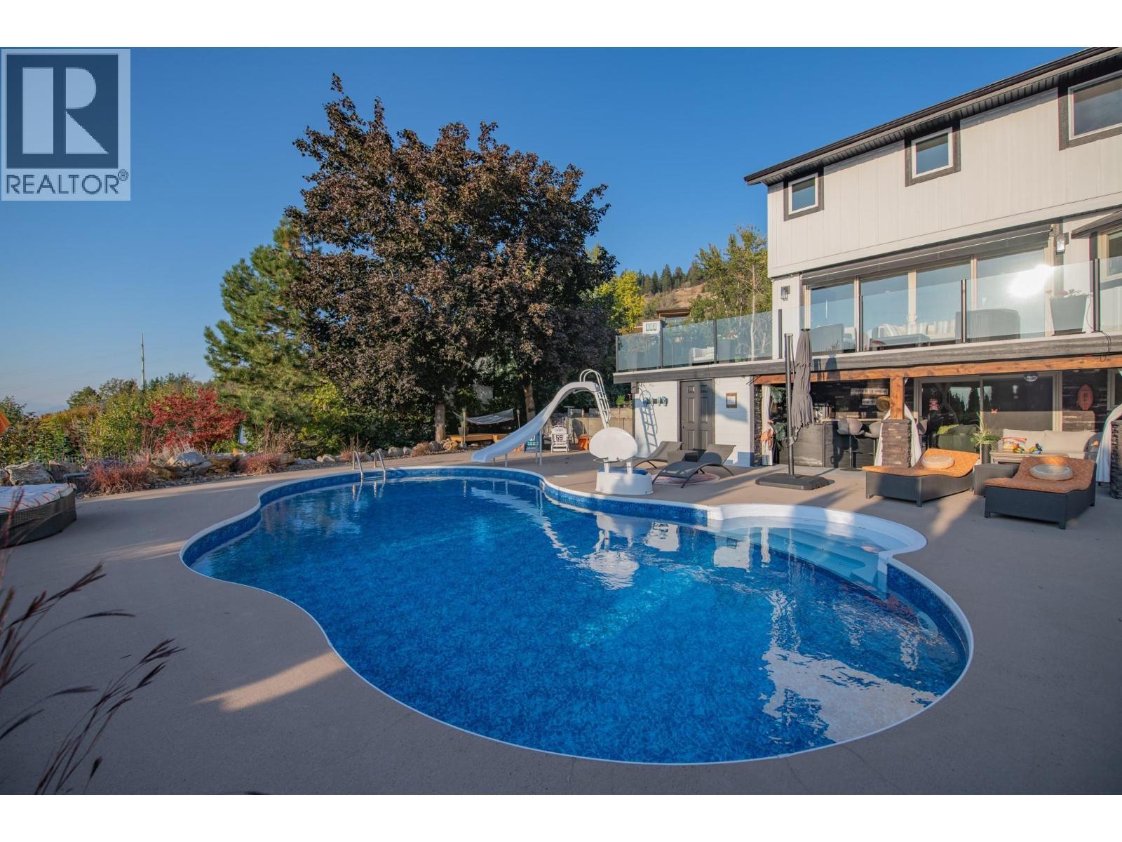 Concrete patio all around - 702 Cypress Drive, Coldstream, BC - Outdoor With In Ground Pool With Deck Patio Veranda With Backyard