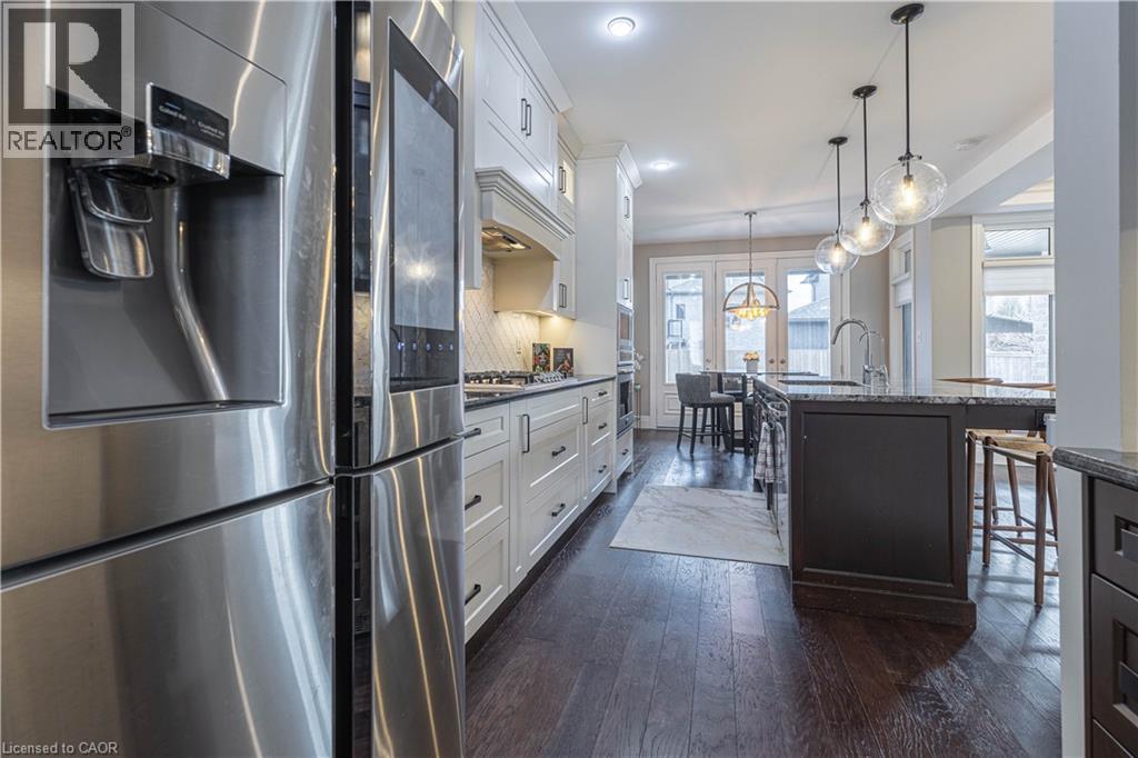 Dual tone kitchen with stainless steel appliances, dual tone cabinetry, dark wood-style flooring, dark stone counters, and a kitchen breakfast bar - 2719 Torrey Pines Way, London, ON - Indoor Photo Showing Kitchen With Upgraded Kitchen