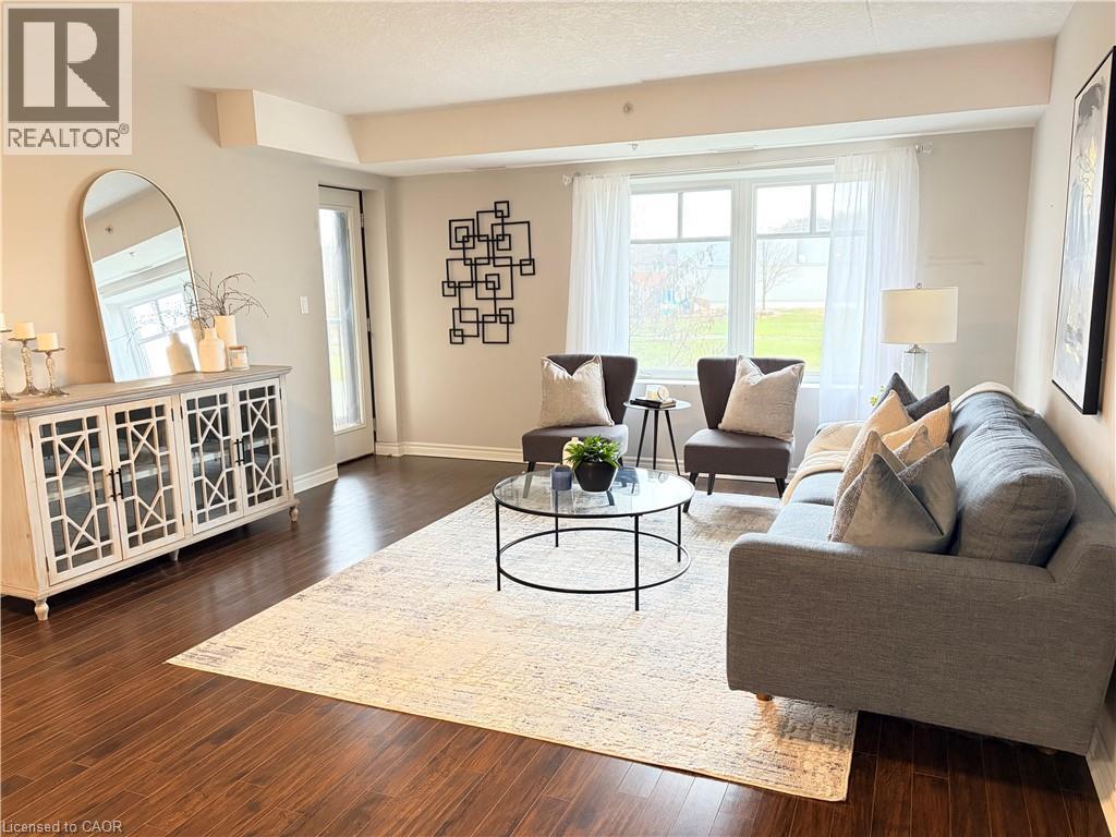Living area with dark wood finished floors, plenty of natural light, and a textured ceiling - 776 Laurelwood Drive Unit# 406, Waterloo, ON - Indoor Photo Showing Living Room