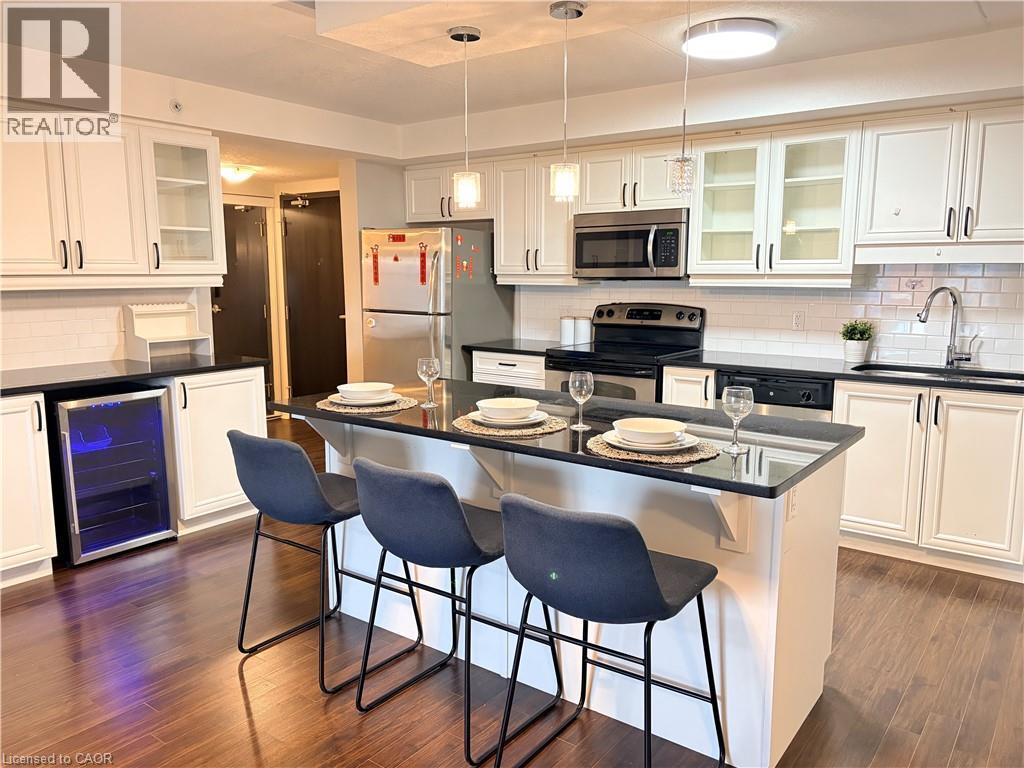 Kitchen featuring glass insert cabinets, decorative backsplash, a kitchen bar, and white cabinetry - 776 Laurelwood Drive Unit# 406, Waterloo, ON - Indoor Photo Showing Kitchen With Stainless Steel Kitchen