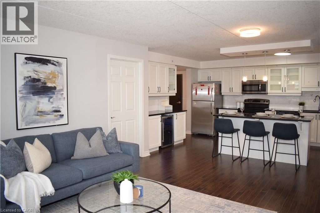 Living room with a textured ceiling, dark wood-style floors, and beverage cooler - 776 Laurelwood Drive Unit# 406, Waterloo, ON - Indoor