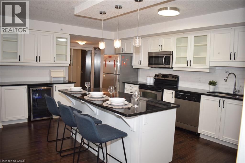 Kitchen featuring glass insert cabinets, backsplash, stainless steel appliances, a breakfast bar area, and white cabinetry - 776 Laurelwood Drive Unit# 406, Waterloo, ON - Indoor Photo Showing Kitchen With Stainless Steel Kitchen With Upgraded Kitchen