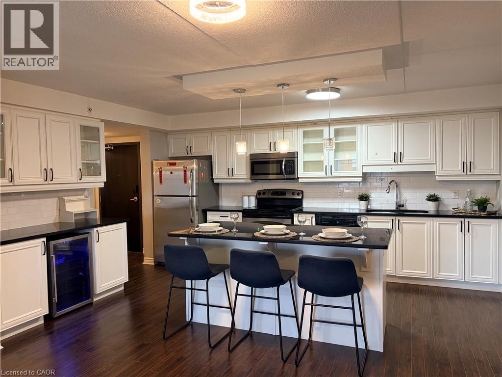 Kitchen with glass fronted cabinets, tasteful backsplash, white cabinets, hanging light fixtures, and a textured ceiling - 776 Laurelwood Drive Unit# 406, Waterloo, ON - Indoor Photo Showing Kitchen With Stainless Steel Kitchen