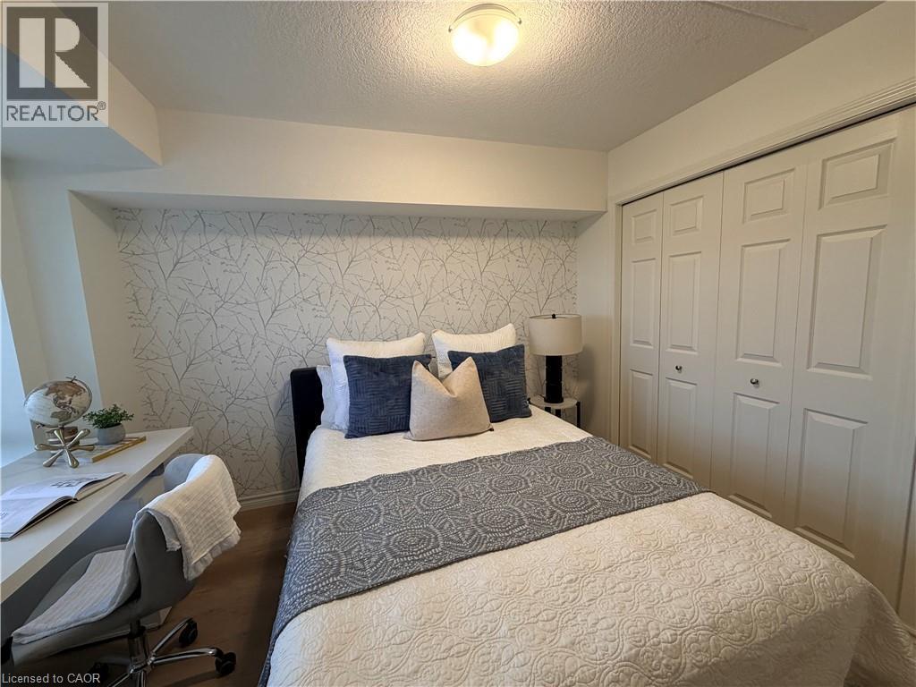 Bedroom with a closet, a textured ceiling, a desk, and wood finished floors - 776 Laurelwood Drive Unit# 406, Waterloo, ON - Indoor Photo Showing Bedroom
