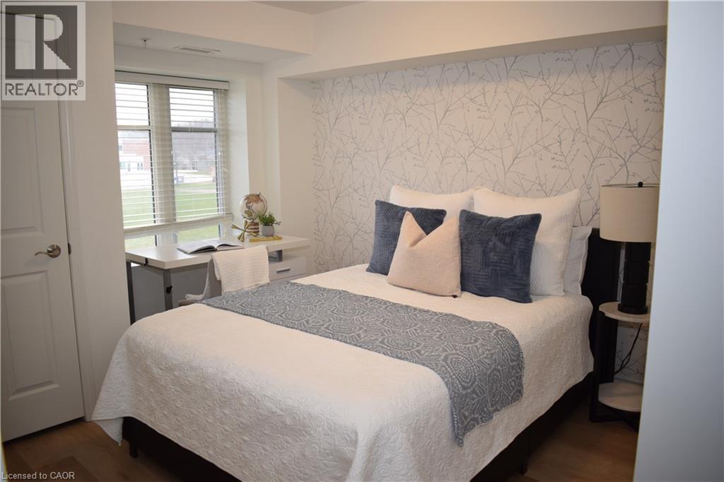 Bedroom featuring wallpapered walls, an accent wall, and wood finished floors - 776 Laurelwood Drive Unit# 406, Waterloo, ON - Indoor Photo Showing Bedroom