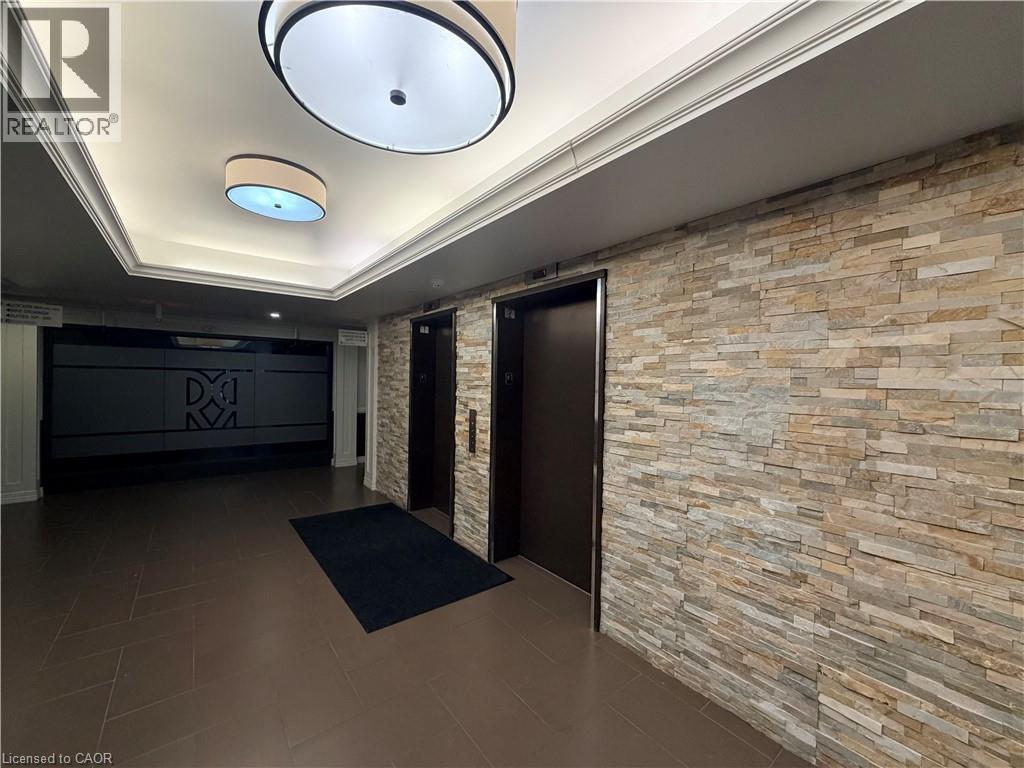 Hallway featuring elevator, dark tile patterned flooring, and a raised ceiling - 776 Laurelwood Drive Unit# 406, Waterloo, ON - Indoor Photo Showing Other Room